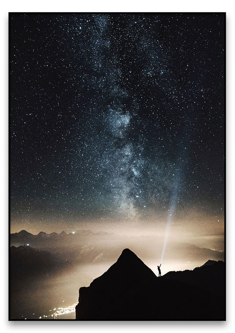 Eine Person steht auf einem Berggipfel und betrachtet den Sternenauflauf.