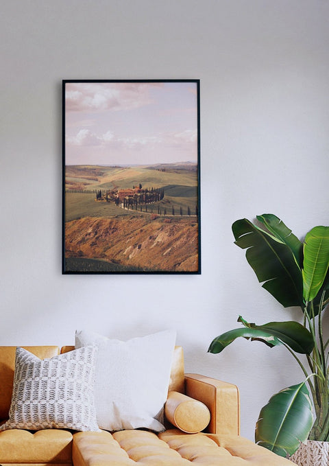 Ein Wohnzimmer mit einer Couch und einer gerahmten Toscana-Landschaft.