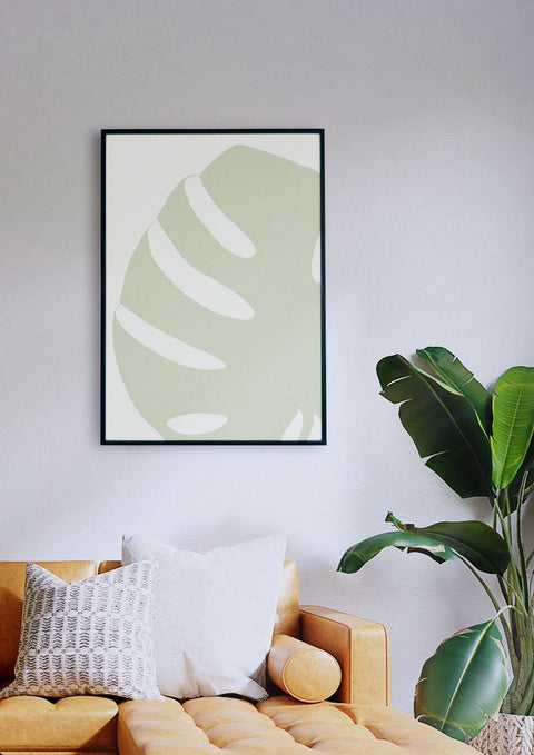 Ein Wohnzimmer mit einer Couch und einer grünen Monstera-03-Blatt-Malerei.
