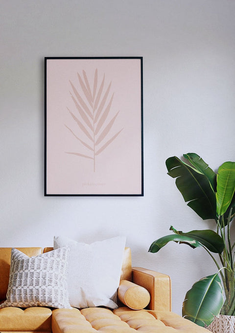 Ein Wohnzimmer mit einer rosa Couch, einem Palmativ 01-Druck an der Wand und einem Gefühl von Naturverbundenheit.