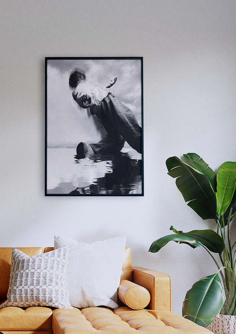 Ein Schwarz-Weiß-Foto einer Person auf einem Surfbrett, das über einer Couch hängt.