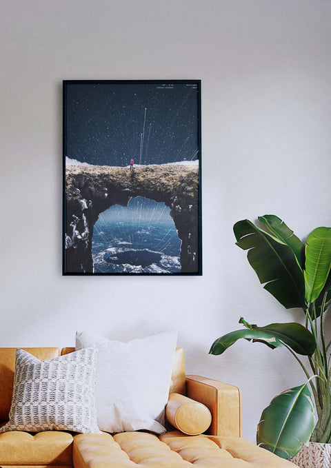 Ein Wohnzimmer mit einer Couch und einem gerahmten Bild eines Sternenhimmels, mit surrealer Fotografie einer Landschaft am Rande eines Klippenbarringers.
