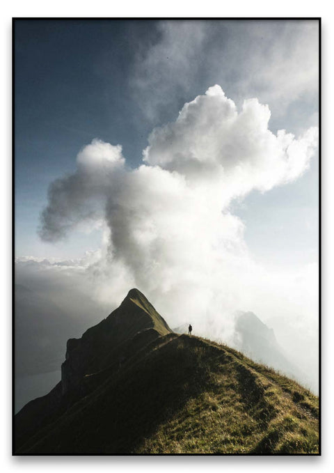 Eine Person steht auf einem Berg und Mann mit Wolken am Himmel.