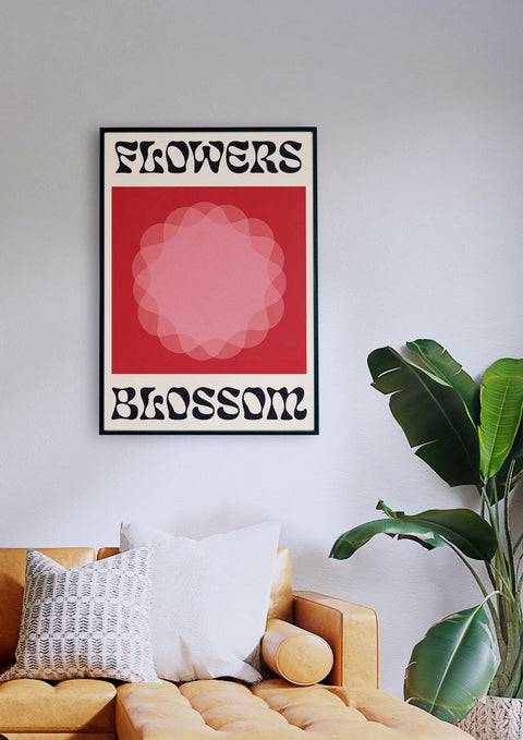 Ein Wohnzimmer mit einer Couch und einem Poster mit der Aufschrift „Flowers Blossom Red“ in markanter Typografie.