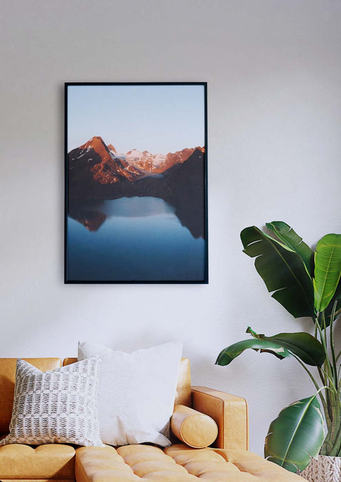 Ein Wohnzimmer mit einer gletscherblauen Couch und einem gerahmten Bild eines Bergsees bei Sonnenuntergang.