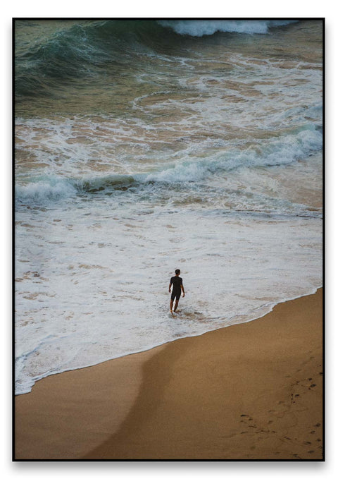 Ein einsamer Junge, der am Strand im Wasser spaziert.