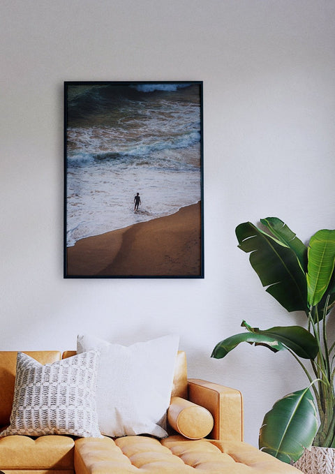 Ein einsamer Junge in einem Wohnzimmer mit einem Bild eines Surfers am Strand.