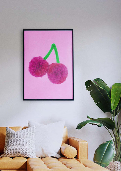 Ein Wohnzimmer mit einer rosa Couch, Pompons und einem Pop a Cherry-Gemälde.