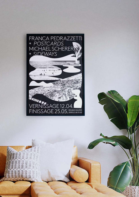 Über einer Couch im Wohnzimmer hängt ein schwarz-weißes Poster mit dem Titel „Postcards and Sideways“.