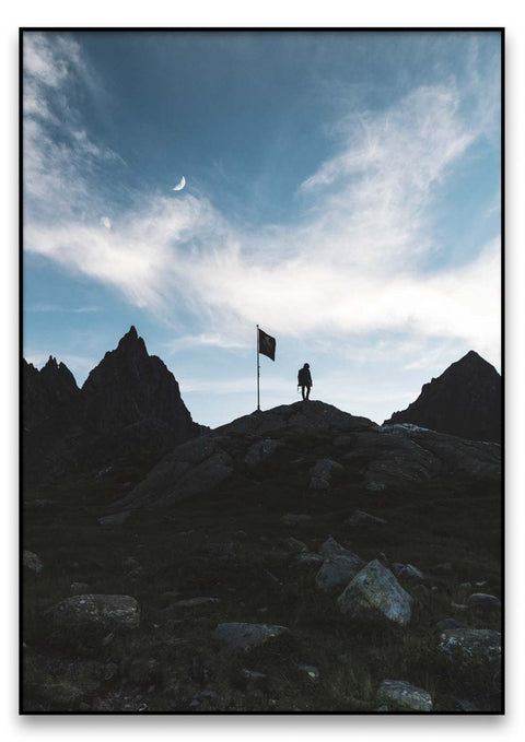 Eine Person steht mit einer Fahne auf einem Berggipfel, aufgenommen im Schillerlicht.