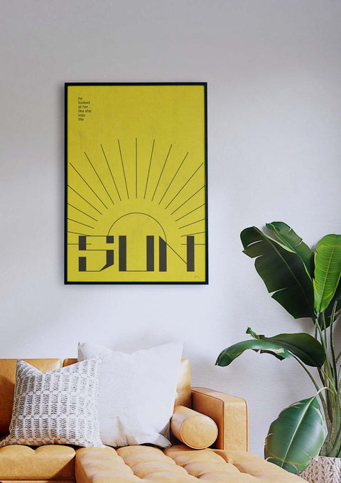 Über einer Couch im Wohnzimmer hängt ein gelbes Sun-Poster mit Grafik Design.