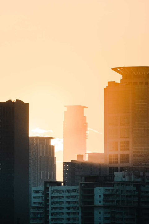 Der Sonnenuntergang wirft einen warmen Schein auf die Skyline der Stadt mit den Silhouetten der Hochhäuser.
