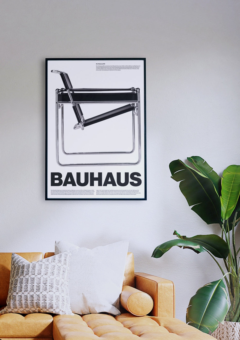 Ein gerahmtes schwarz-weißes BAUHAUS B3-Poster hängt an einer weißen Wand über einem senfgelben Sofa mit zwei Kissen. Rechts neben der Couch steht eine grüne Topfpflanze.