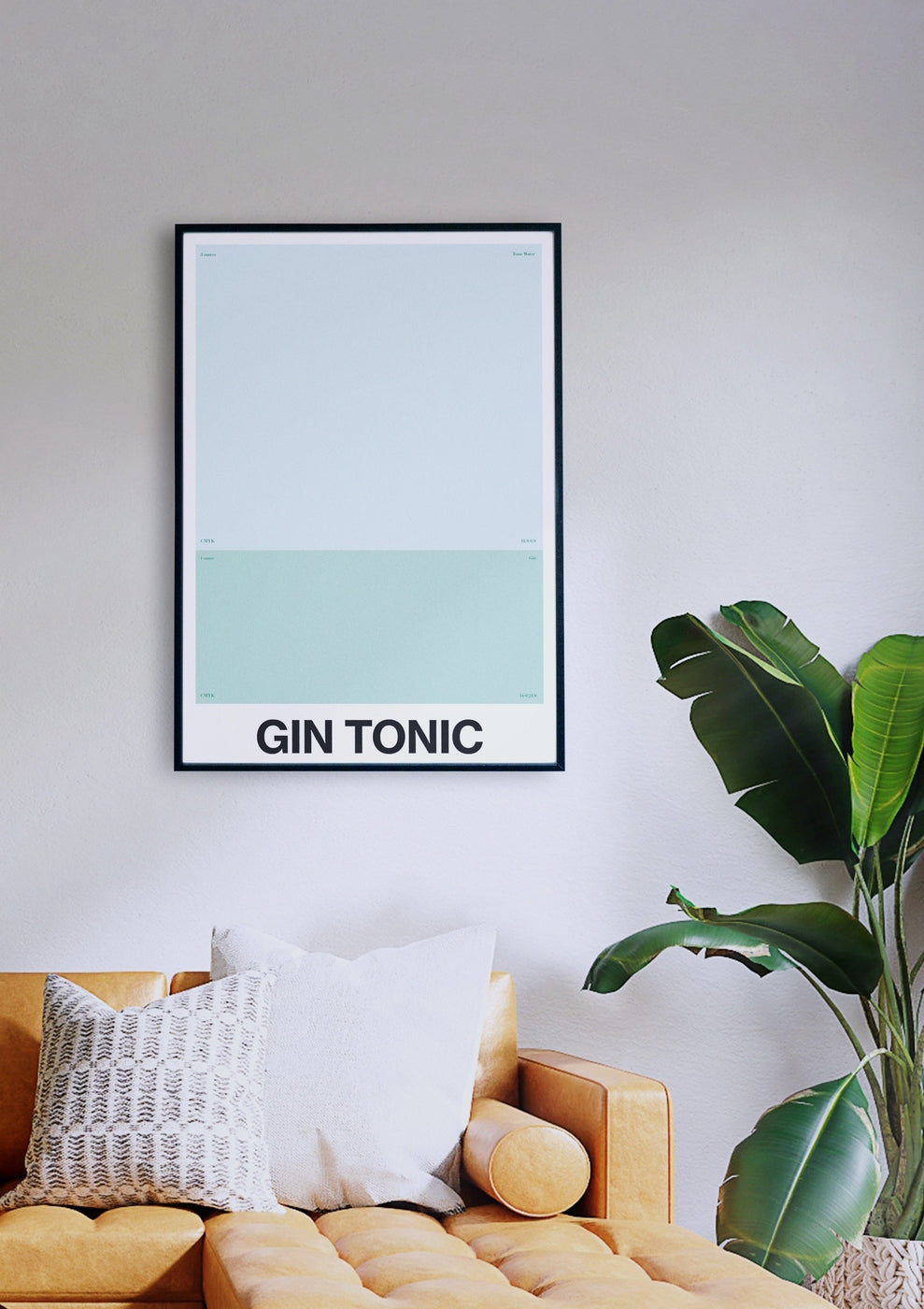 Ein minimalistisches GIN TONIC-Poster, gerahmt und hängend an einer hellen Wand über einem gelben Sofa mit einem gemusterten Kissen, neben einer grünen Pflanze.