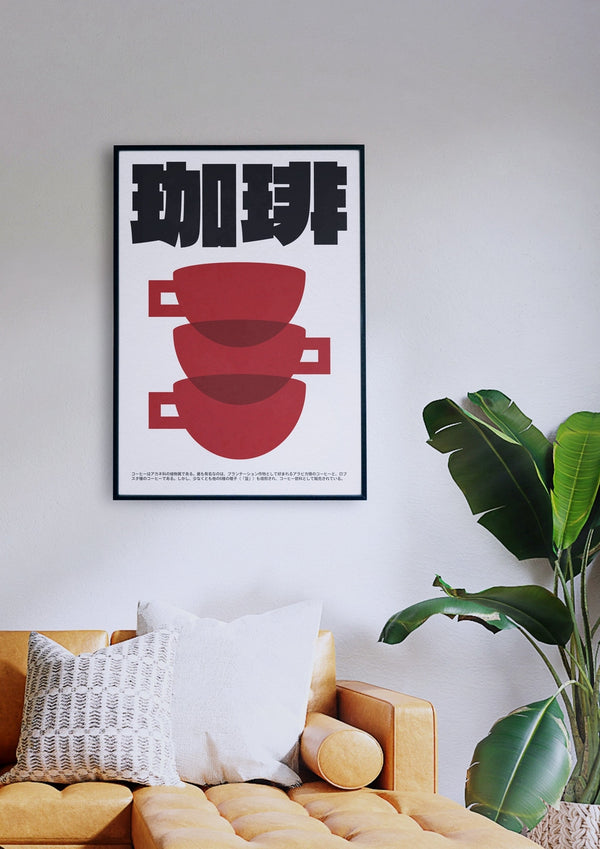 Ein gerahmtes Poster „Japanische Kaffeekultur“ mit zwei roten Kaffeetassen und schwarzem Text hängt an einer weißen Wand über einem gelben Sofa mit weißen Kissen. Rechts neben dem Sofa steht eine grüne Pflanze.