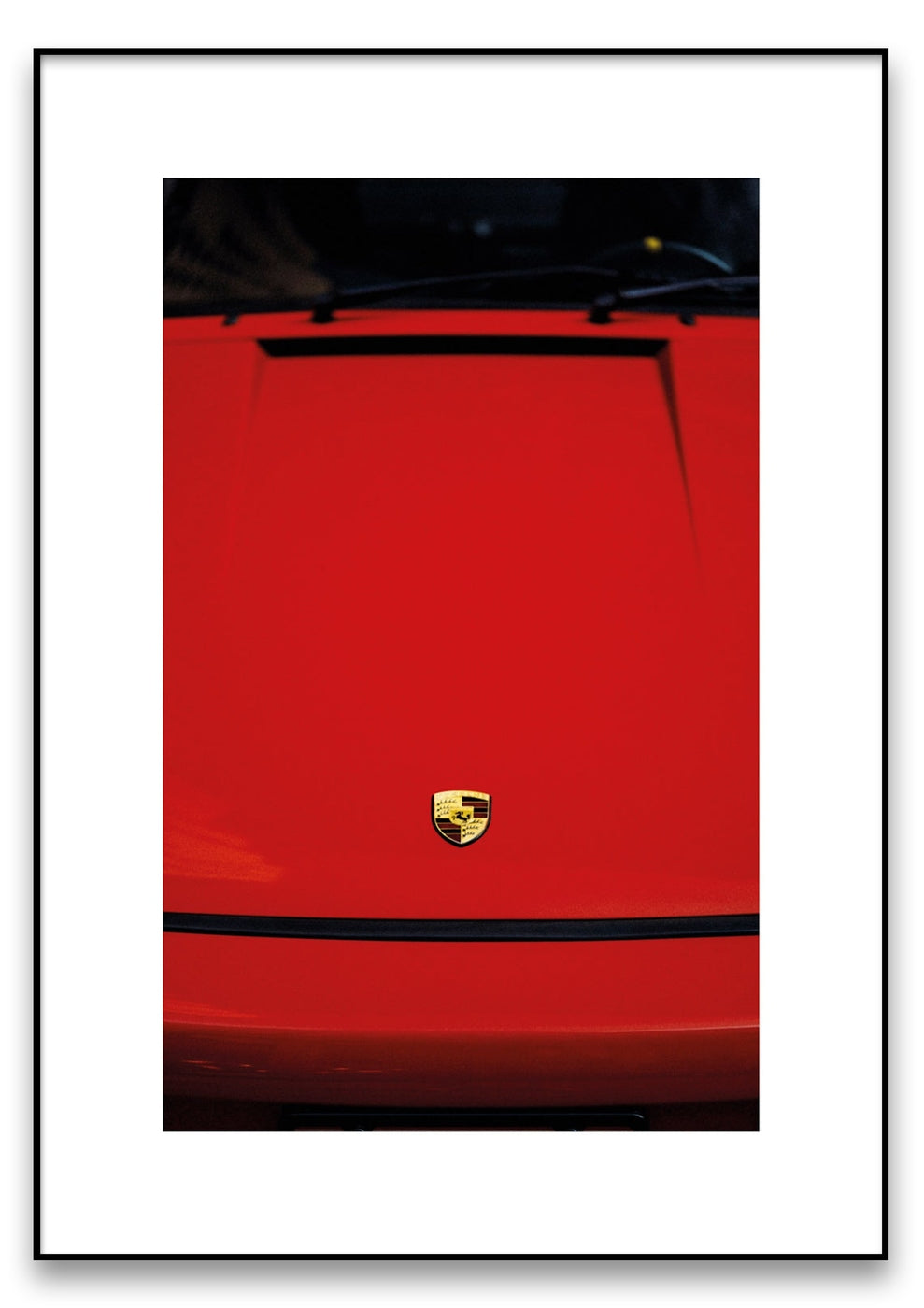 Nahaufnahme der Front eines Porsche Rot mit Porsche-Logo auf der Motorhaube. Das Bild ist mit einem weißen Rand eingerahmt.