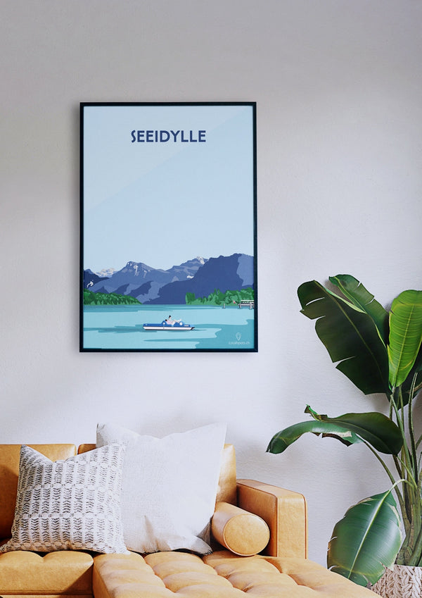 Ein gerahmtes Poster mit dem Titel „Seeidylle“, das eine Seeszene zeigt, hängt über einem hellbraunen Sofa mit weißen und senffarbenen Kissen. Neben der Couch steht eine grüne Pflanze.