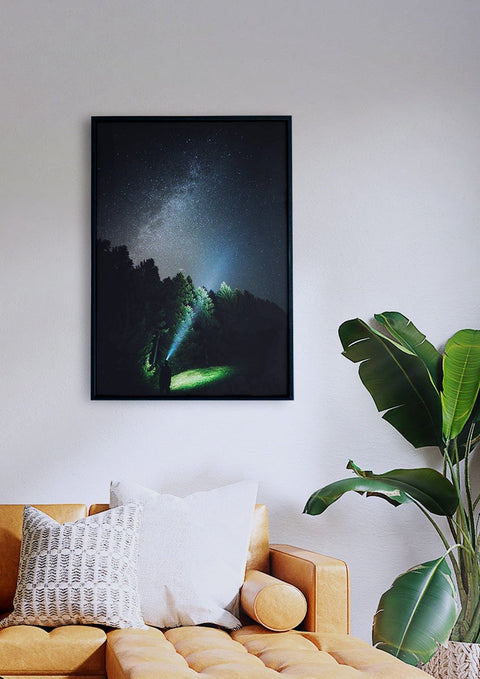 Ein Foto eines Sternenstaubhimmels, der über einer Couch in einem Wohnzimmer hängt.