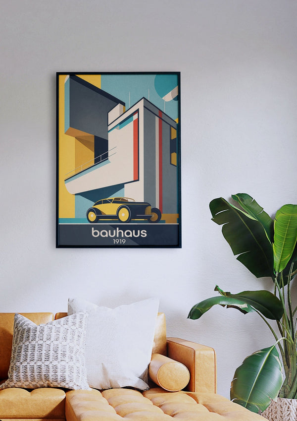 Ein gerahmtes „Bauhaus Bauten 3“-Poster, das ein Gebäude und ein Auto zeigt, hängt an einer weißen Wand über einem senfgelben Sofa mit Kissen, während neben dem Sofa eine grüne Topfpflanze steht.