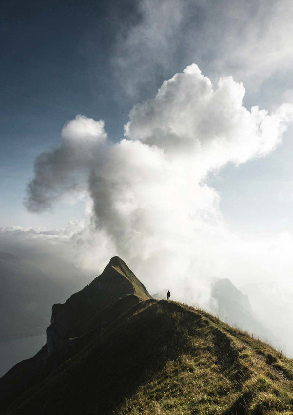 Eine Person, die auf einem Berg und Mann steht, mit Wolken im Hintergrund.