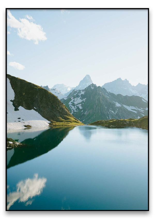 Ein Bergsee mit azurblauen Frühsommer und Bergen in der alpinen Landschaft im Hintergrund.