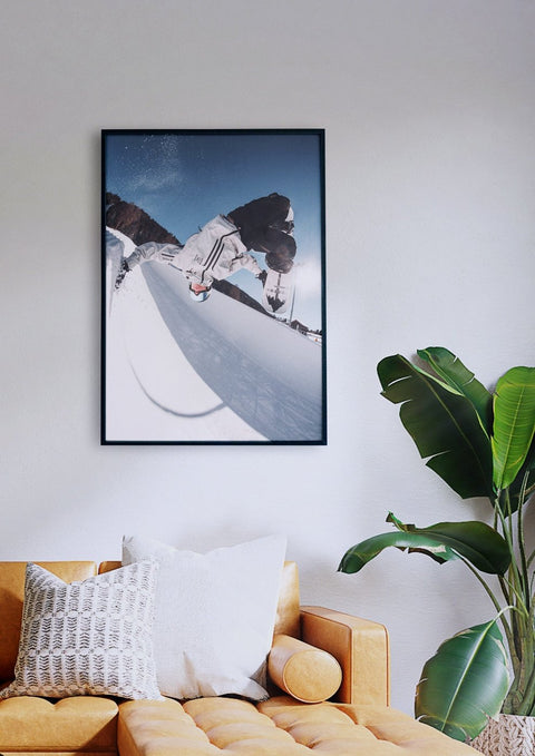 Ein gerahmtes Foto eines Snowboarders, der in einem Wohnzimmer ein Halfpipe-Manöver ausführt.