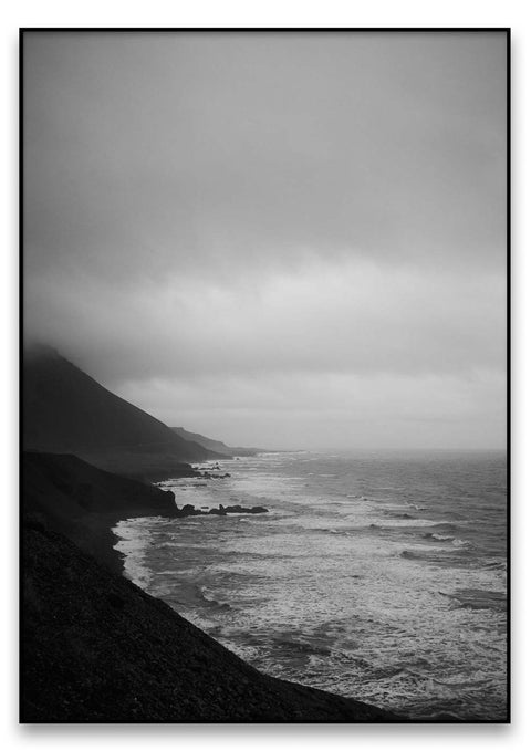 Eine schwarz-weiße Fotografie von einer Küstenlandschaft und dem Ozean in Island.