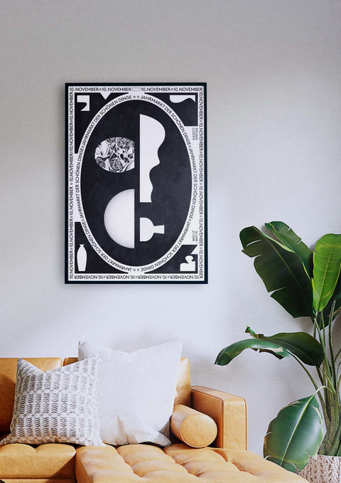 Ein Wohnzimmer mit einer Couch und einem schwarz-weiß gerahmten Druck von „Jahrmarkt der schönen“.