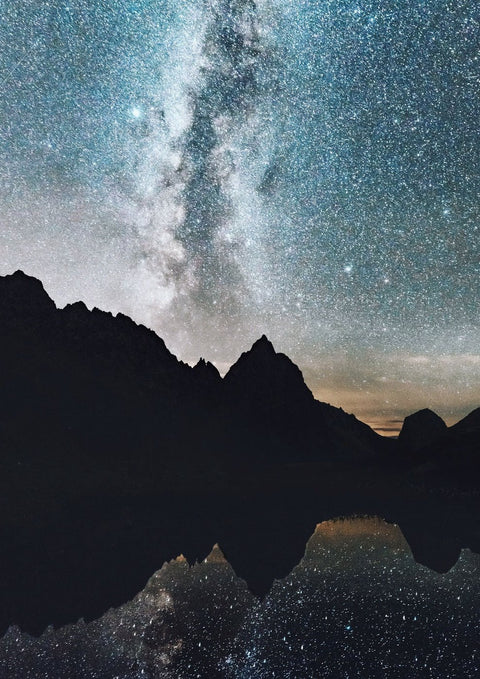 Eine Gebirgssilhouette mit Milchstraße im Hintergrund.