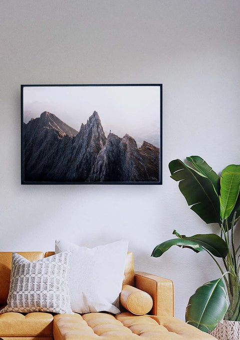 Ein Wohnzimmer mit einem an der Wand montierten Fernseher, auf dem ein Foto der Morgenstunde über dem Berggipfel zu sehen ist.
