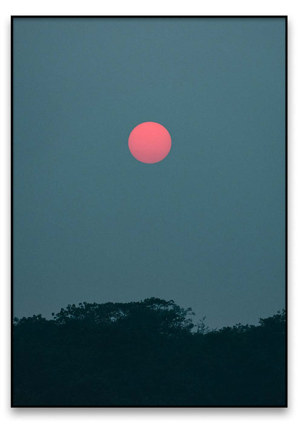 Eine rote aufgehende Sonne am Himmel mit Bäumen im Natur-Hintergrund.