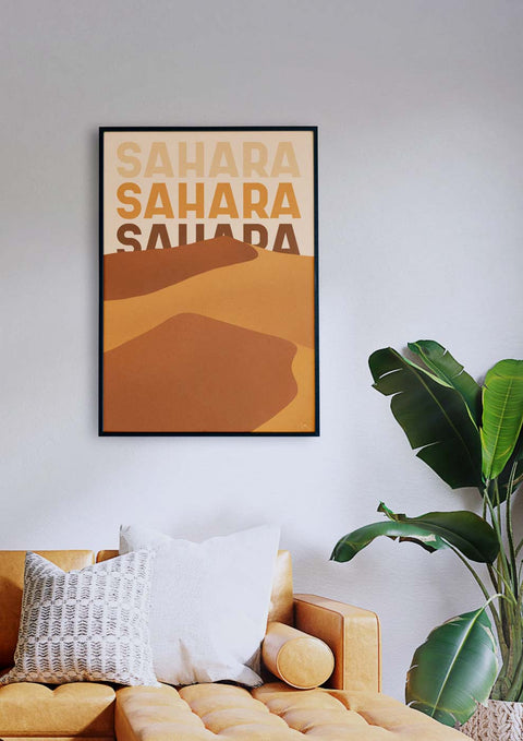 Ein Wohnzimmer mit einem beigen Sofa und einem Sahara-Poster mit dem Wort „Sahara“ in eleganter Typografie.