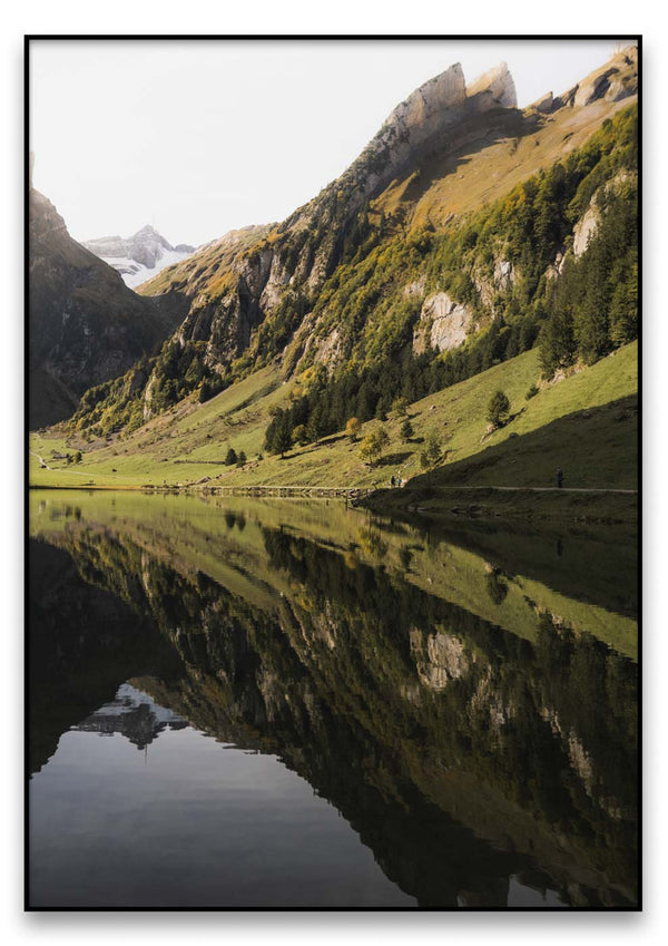 Ein Seealpsee, umgeben von Bergen und Bäumen, der ein perfektes Spiegelbild der Natur bietet.