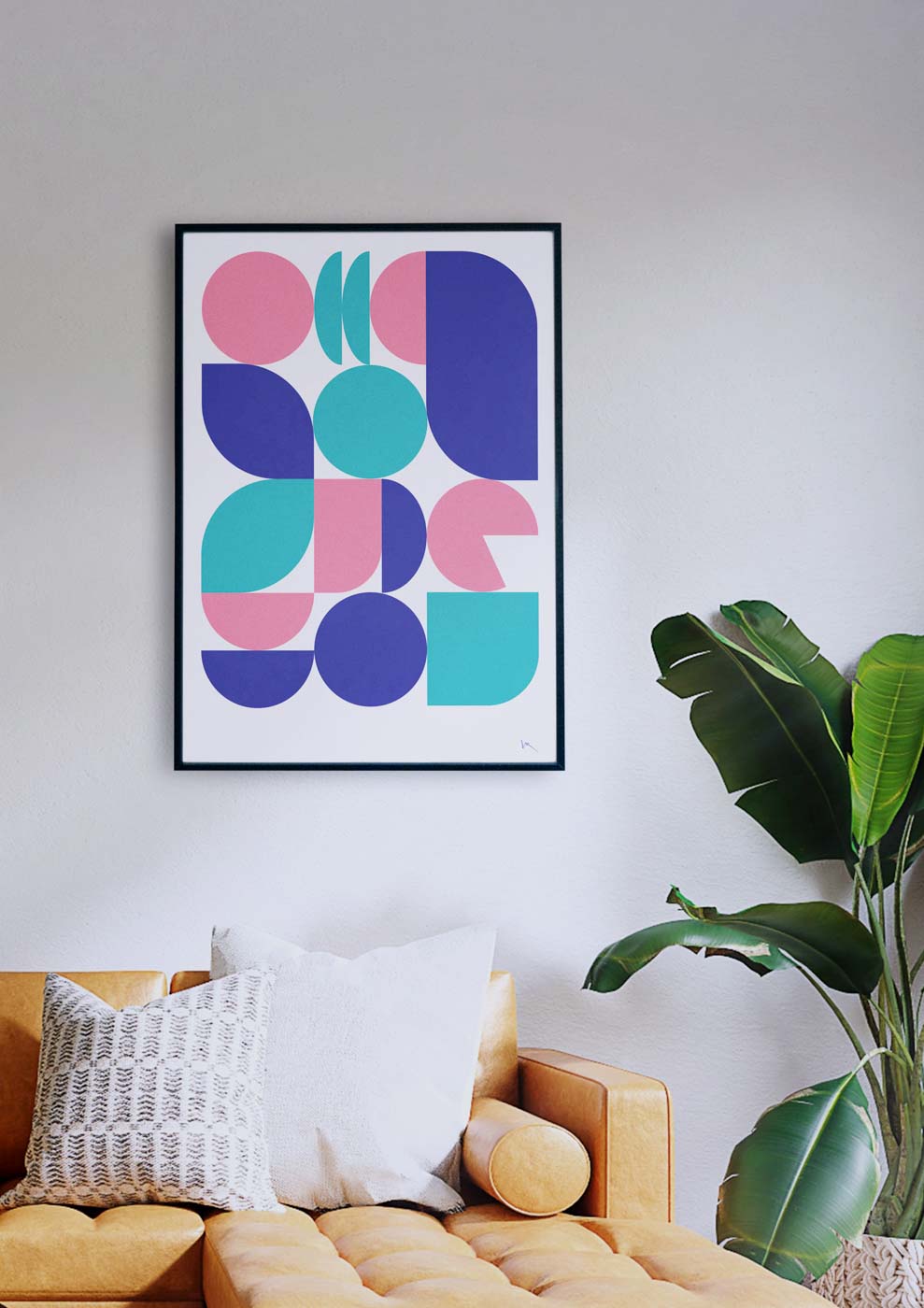 Ein Wohnzimmer mit einer Couch und einem rosa-blau gerahmten Bild mit „Shapes II“.