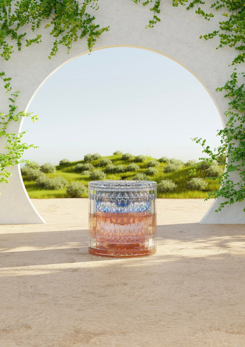 Eine sonnige Tagesdarstellung eines Glasgefäßes, das auf einer Terrasse steht und von Pflanzen umgeben ist.