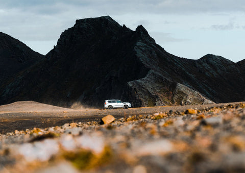 Ein weißer SUV fährt durch eine Wüstenlandschaft mit Bergen im Hintergrund.