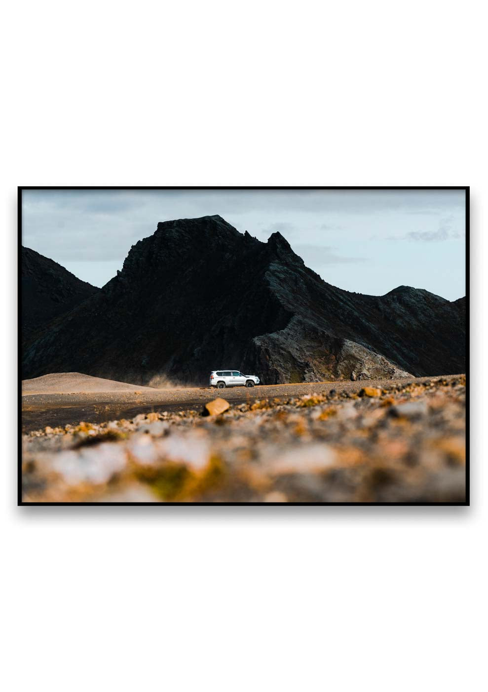 Ein weißes Auto, das eine Straße entlangfährt, mit Bergen im Hintergrund, atemberaubend eingefangen, wenn es hart auf hart kommt.